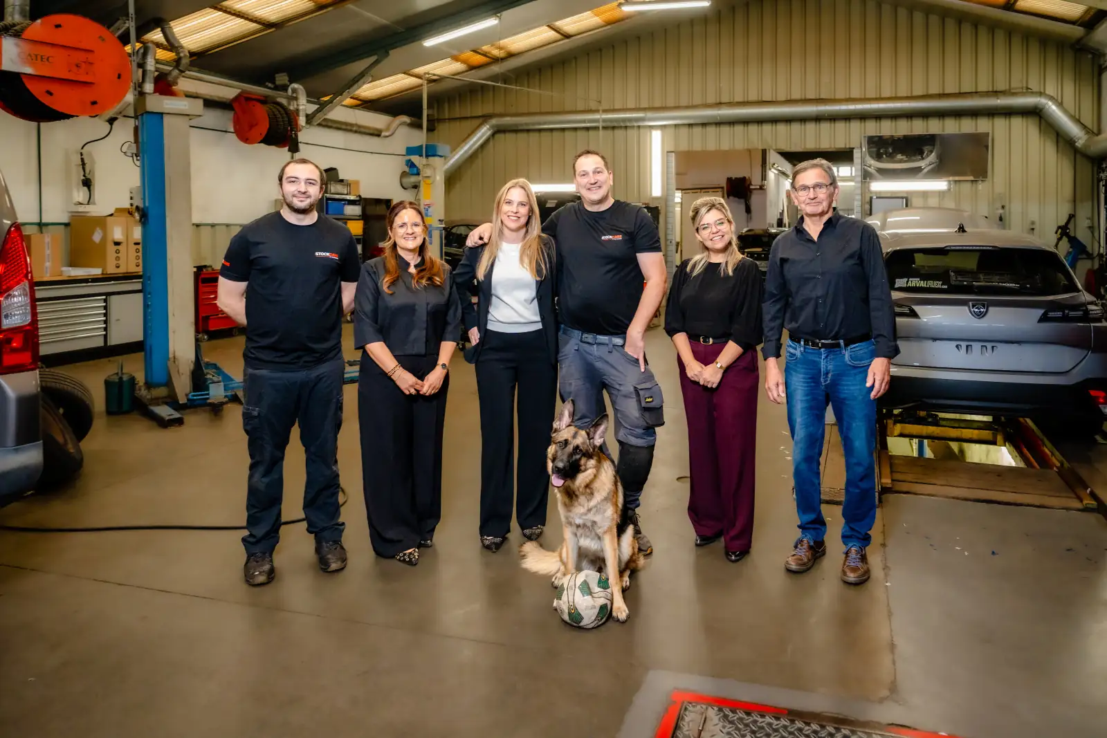 Het team van StockCars in de werkplaats, met de hond